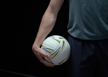 Antrenman öncesi voleybol topunu elinde tutan sporcunun kol ve gövde detayı.