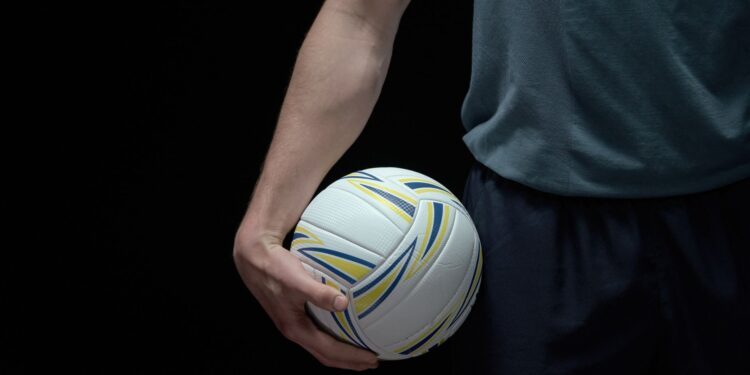 Antrenman öncesi voleybol topunu elinde tutan sporcunun kol ve gövde detayı.