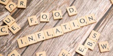 Ahşap masa üzerinde SCRABBLE harfleriyle 'INFLATION' yazısı oluşturulmuş.