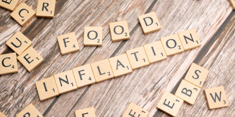 Ahşap masa üzerinde SCRABBLE harfleriyle 'INFLATION' yazısı oluşturulmuş.