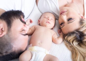 Yatmakta olan bir bebek ile anne ve babasının yüzlerinin yakın plan görüntüsü.