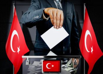 Takım elbiseli bir kişinin oy sandığına oy atma anı.