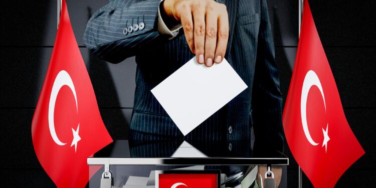 Takım elbiseli bir kişinin oy sandığına oy atma anı.
