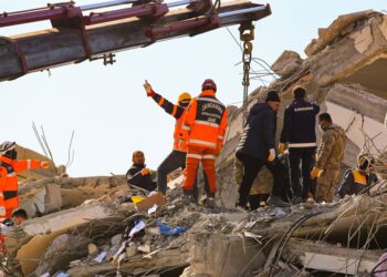 Yıkılmış bir binanın enkazında arama kurtarma çalışmaları yürüten ekipler.