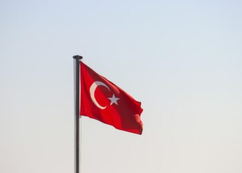 Açık mavi gökyüzü önünde dalgalanan kırmızı renkli Türk bayrağı.