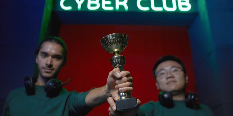 Cyber Club tabelası altında ellerinde kupa tutan iki genç oyuncu.