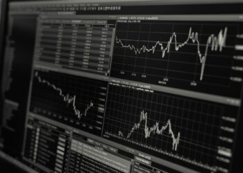 Siyah arka planda finansal grafikler ve hisse senedi piyasası verileri.