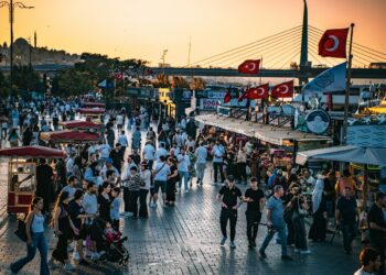 İstanbul'da sahil kenarında yürüyen kalabalık insanlar ve gün batımı manzarası
