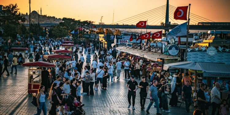 İstanbul'da sahil kenarında yürüyen kalabalık insanlar ve gün batımı manzarası