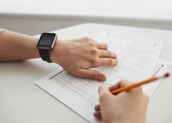 Akıllı saat takan bir aday test kağıdına optik form dolduruyor.