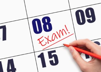 Takvim yaprağı üzerinde kırmızı kalemle sekizinci güne Exam yazan el.