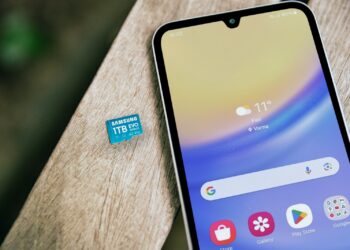 Ahşap masanın üzerinde duran akıllı telefon ve microSD hafıza kartı.