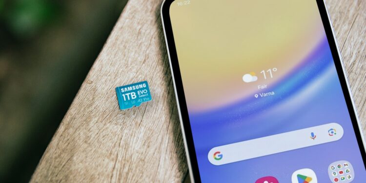 Ahşap masanın üzerinde duran akıllı telefon ve microSD hafıza kartı.