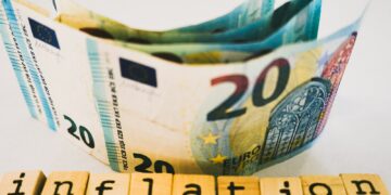 Üzerinde 'inflation' yazan ahşap harfler ve arkasında euro banknotları.