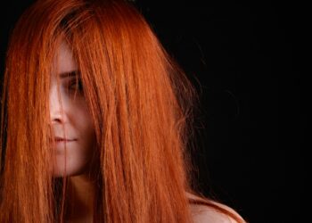 Yüzünün bir kısmı kızıl saçlarla örtülü olan bir kişinin yakın plan portresi.