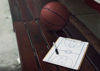 Ahşap bir bank üzerinde duran basketbol topu ve taktik tahtası.