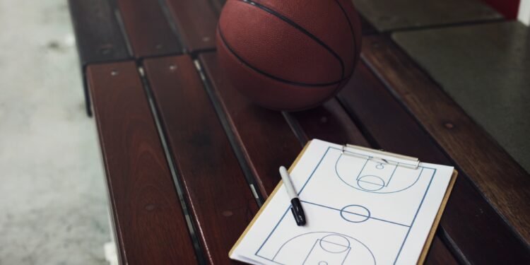 Ahşap bir bank üzerinde duran basketbol topu ve taktik tahtası.