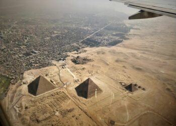 Uçak penceresinden görünen Mısır'daki Giza Piramitleri ve şehir manzarası.