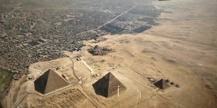 Uçak penceresinden görünen Mısır'daki Giza Piramitleri ve şehir manzarası.
