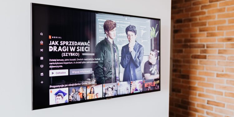 Duvara monte edilmiş televizyon ekranında dizi ve film platformu arayüzü görünmektedir.