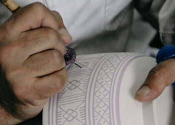 Bir zanaatkar çömlek üzerine ince desenler ve çizgiler çiziyor.