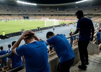 Stadyum tribününde hayal kırıklığıyla ellerini başına koyan futbol taraftarları.